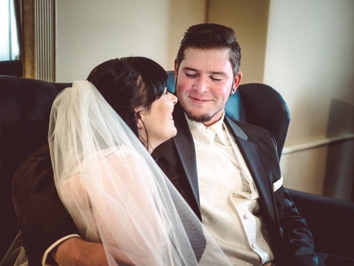 Bräutigan lächelt seine Braut an- Hochzeitspaar sitzt auf einem Sofa im Häckerts Grand Hotel Bad