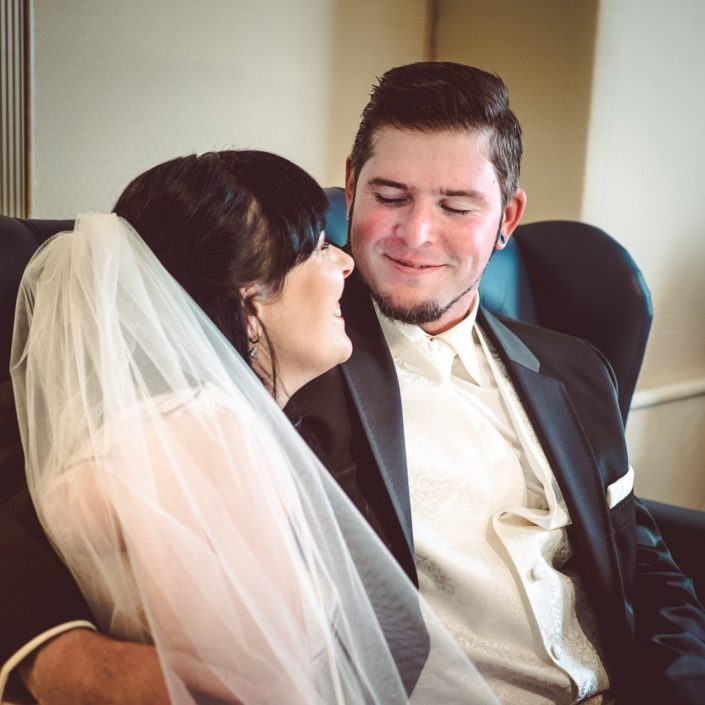 Bräutigan lächelt seine Braut an- Hochzeitspaar sitzt auf einem Sofa im Häckerts Grand Hotel Bad