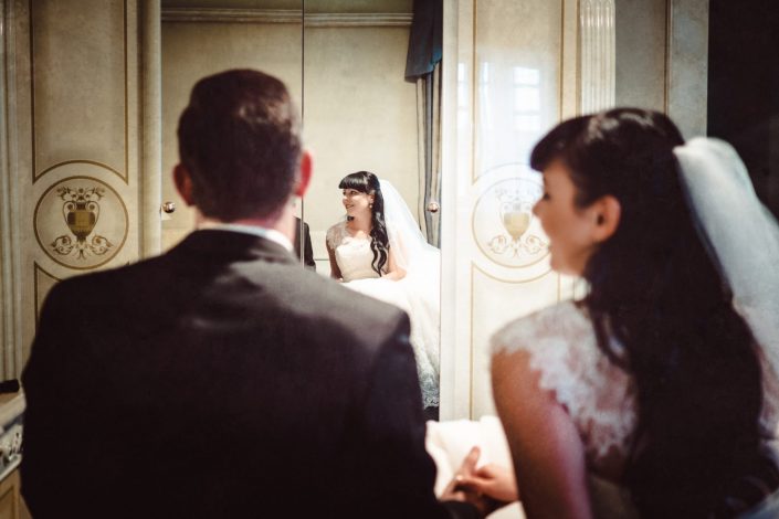 Romantisches Afterwedding Shooting.Hochzeitspaar spiegelt sich in einem Schrank.schaut sich verliebt an.