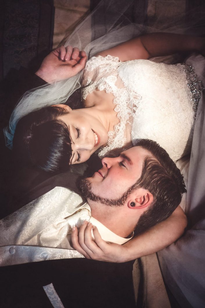 Hochzeitsppar liegt auf einem vintage Bett, Arm in Arm und schaut sich verliebt an.